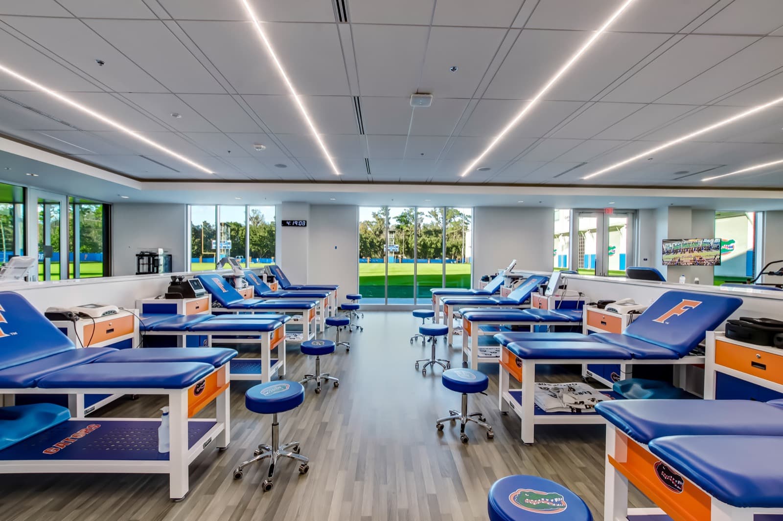 Bill Heavener Football Training Center — recovery suite with motorized roller shades on full-height glazing, Gainesville, FL