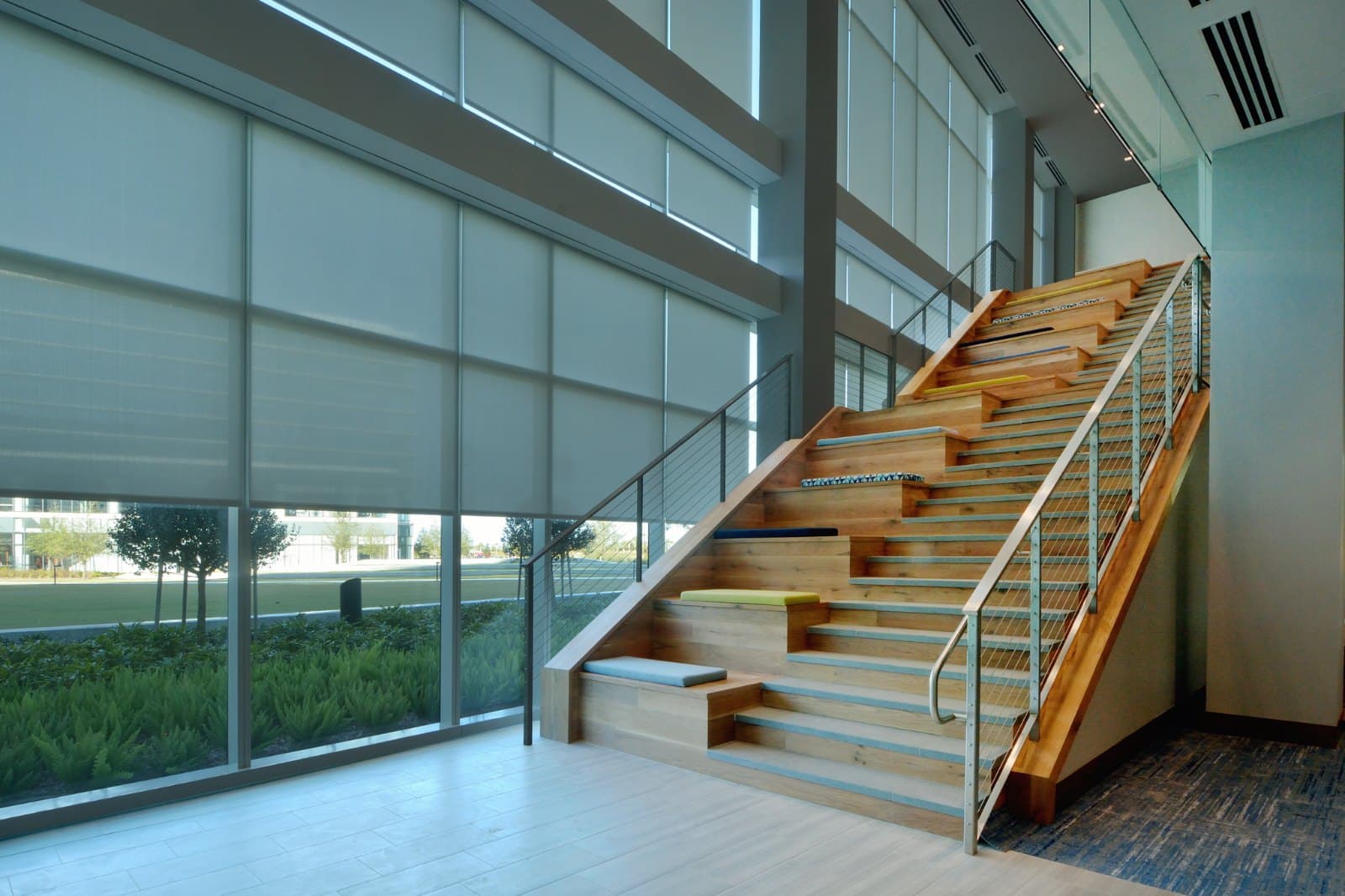 KPMG Lakehouse — open feature stair with motorized roller shades across the curtain-wall glazing